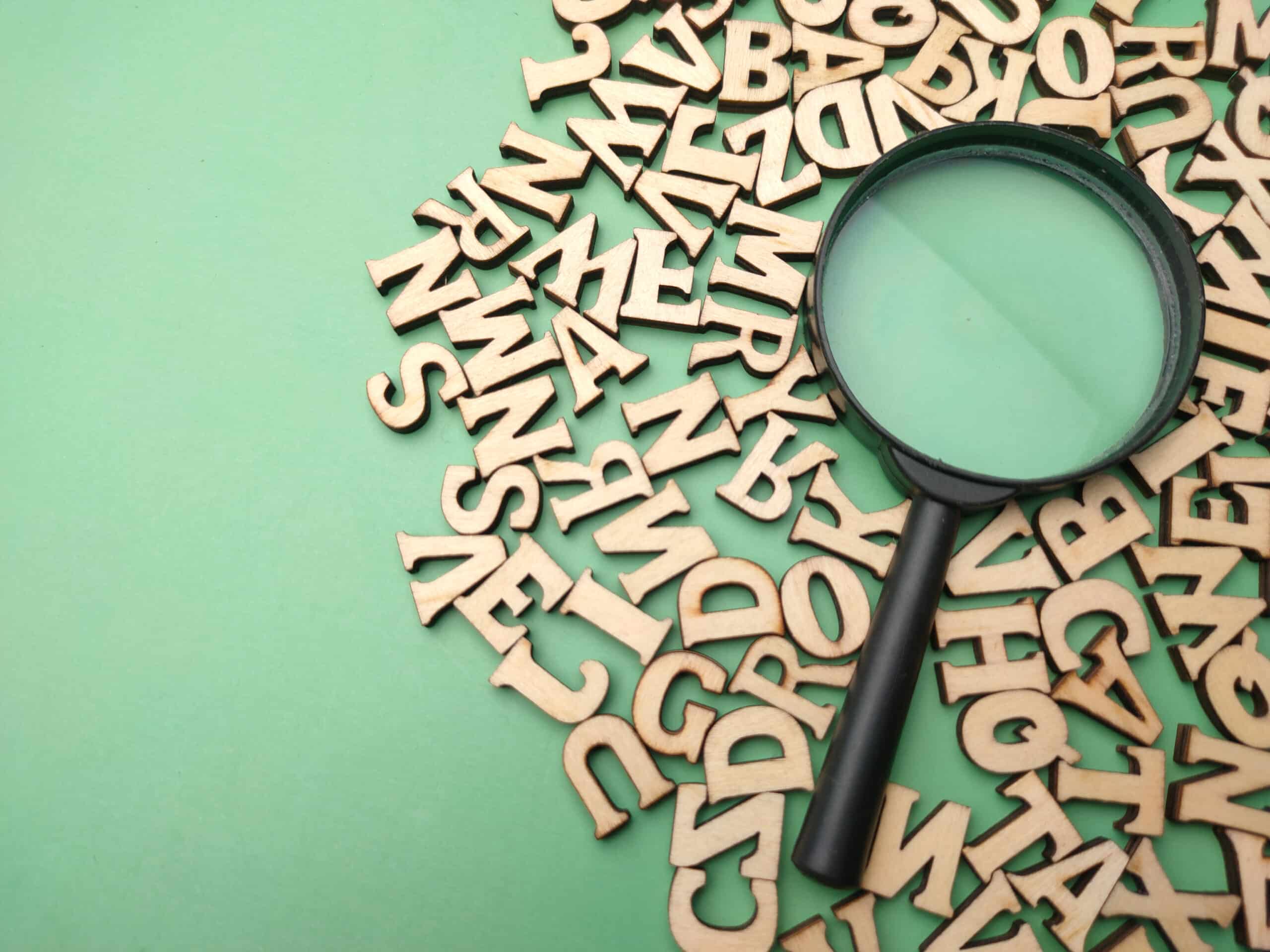 Wooden word and magnifying glass on a green background